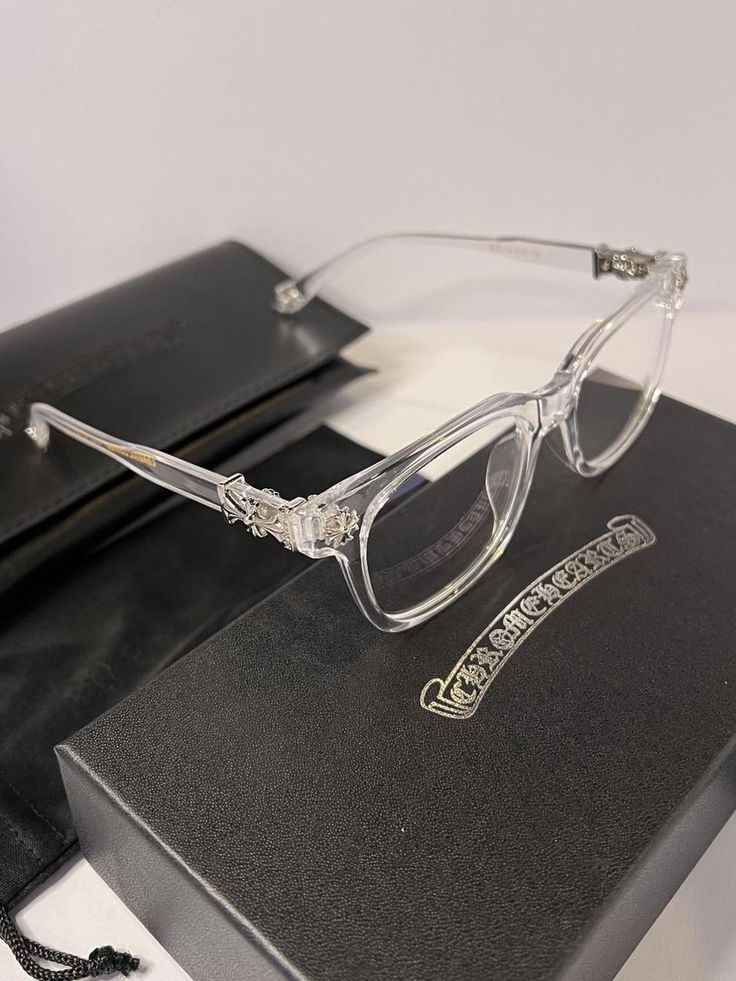 Clear eyeglasses with decorative arm ends on a black box