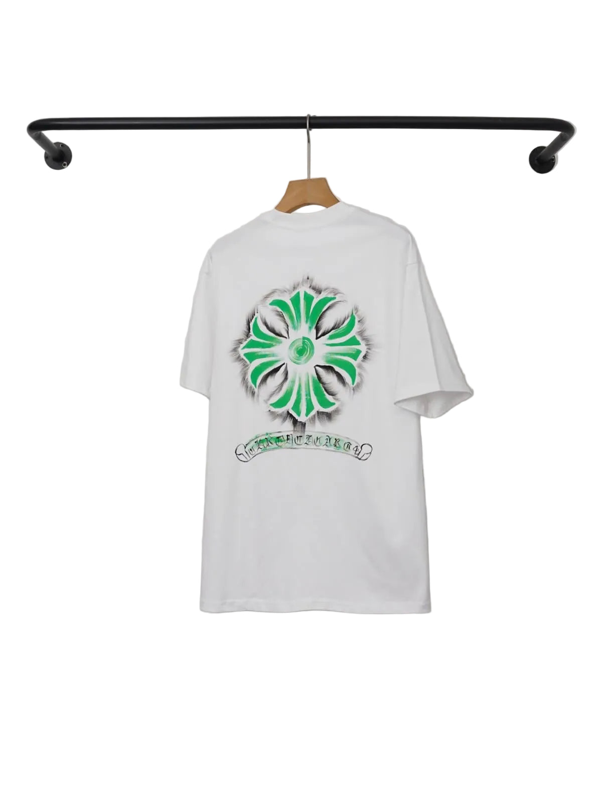 White t-shirt with green floral design hanging on a rack against a white wall.
