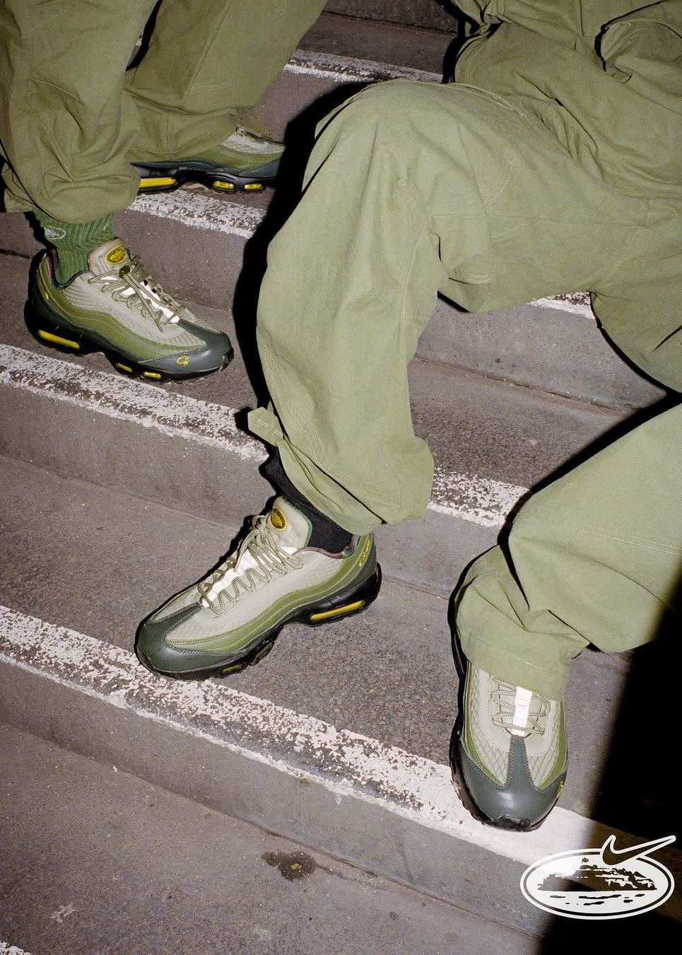 Person wearing green pants and matching sneakers climbing stairs with a Nike logo visible.