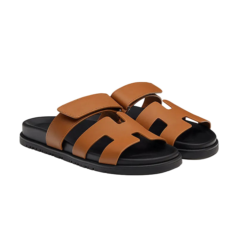 Brown sandals with black soles on a beige background