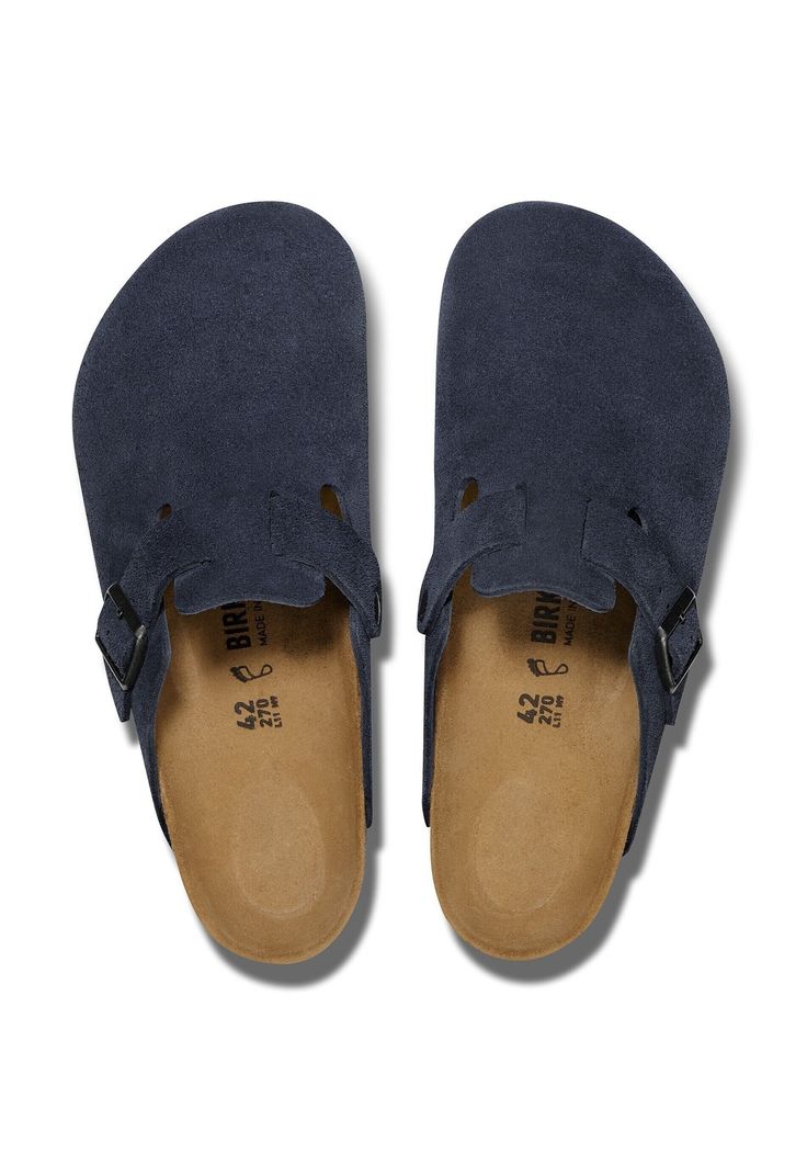 A pair of navy blue suede clogs with tan Birkenstock footbeds, shown from a top-down view on a white background.