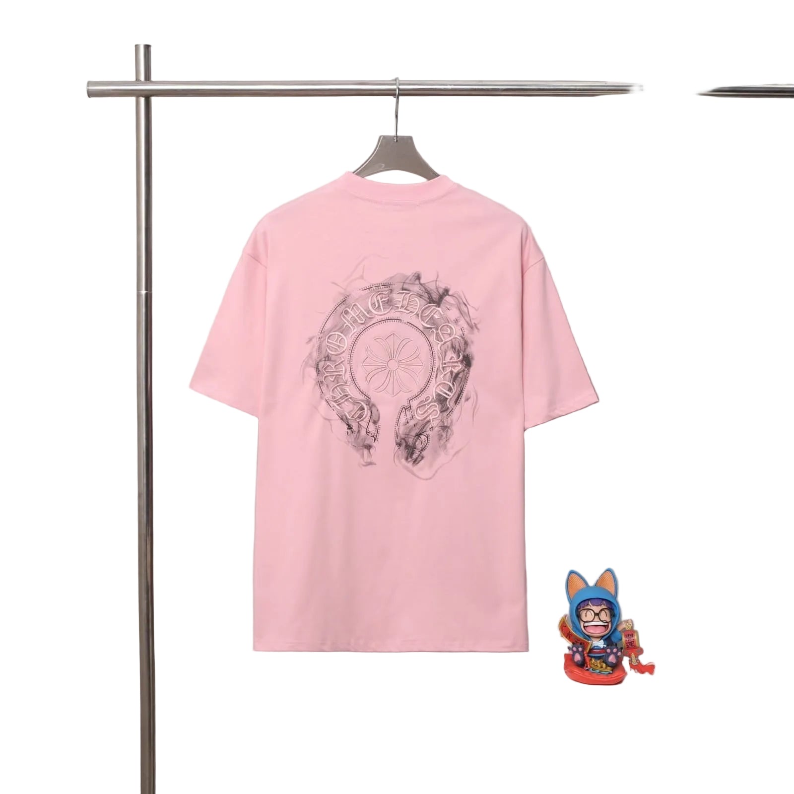 Pink t-shirt with graphic design on a rack against a gray background